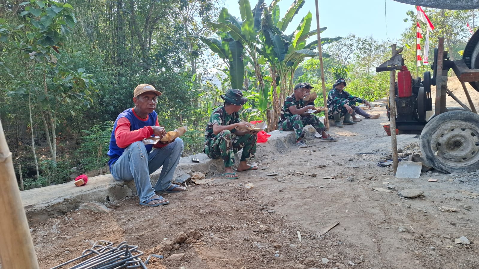 TANPA CANGGUNG, MASYARAKAT BERSAMA ANGGOTA SATGAS TMMD SARAPAN PAGI DISAMPING JEMBATAN